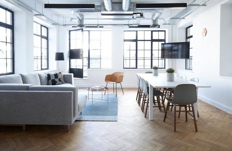 Bright shared lounge with soft seating and a long communal table